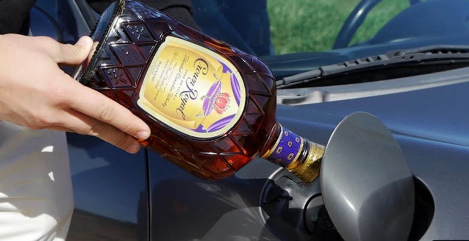 A man pours alcohol into the tank of a car, close-up