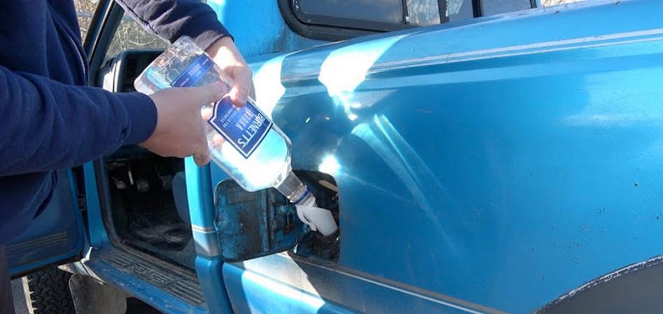 A man pours alcohol into the tank of a car, close-up