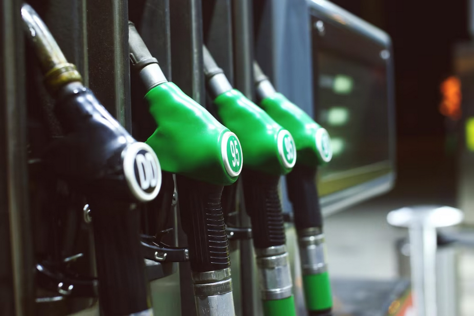 A row of fuel dispensers with green nozzles at a petrol station.