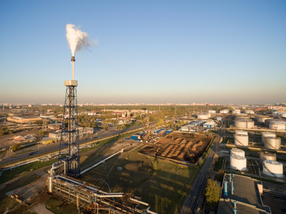 An aerial view of an industrial facility with a smokestack emitting steam