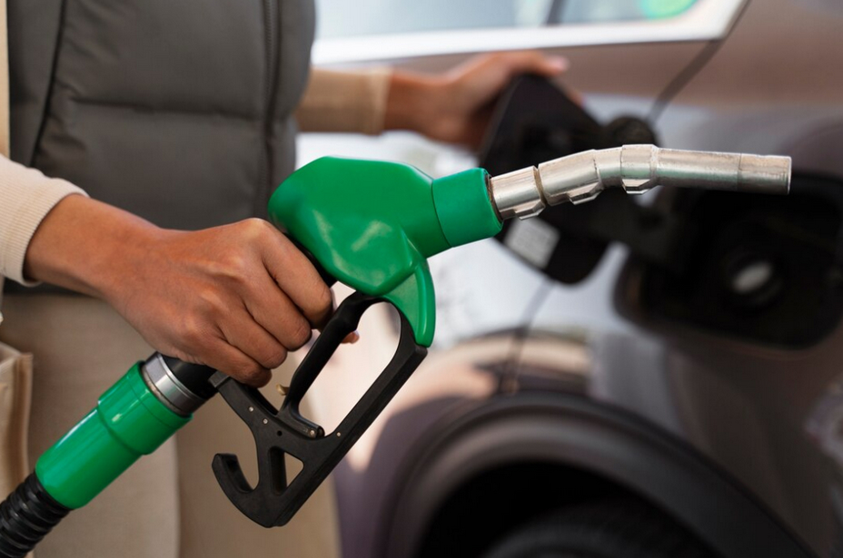 View of woman near car at the gas station holds green gasoline pump nozzle