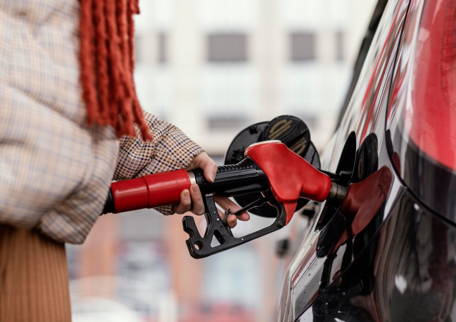 a woman with a gasoline red pump nozzle in a gas station 